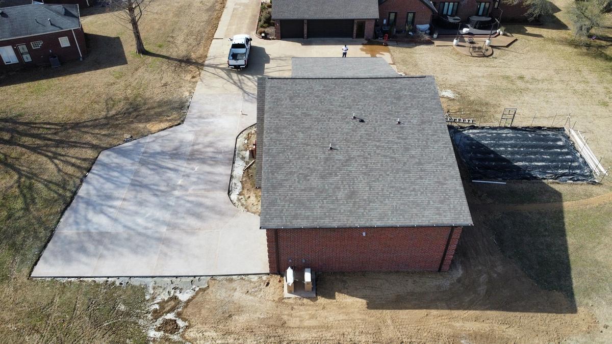 Closer aerial view of the same brick garage's roof and driveway, with a worker standing near a parked truck.