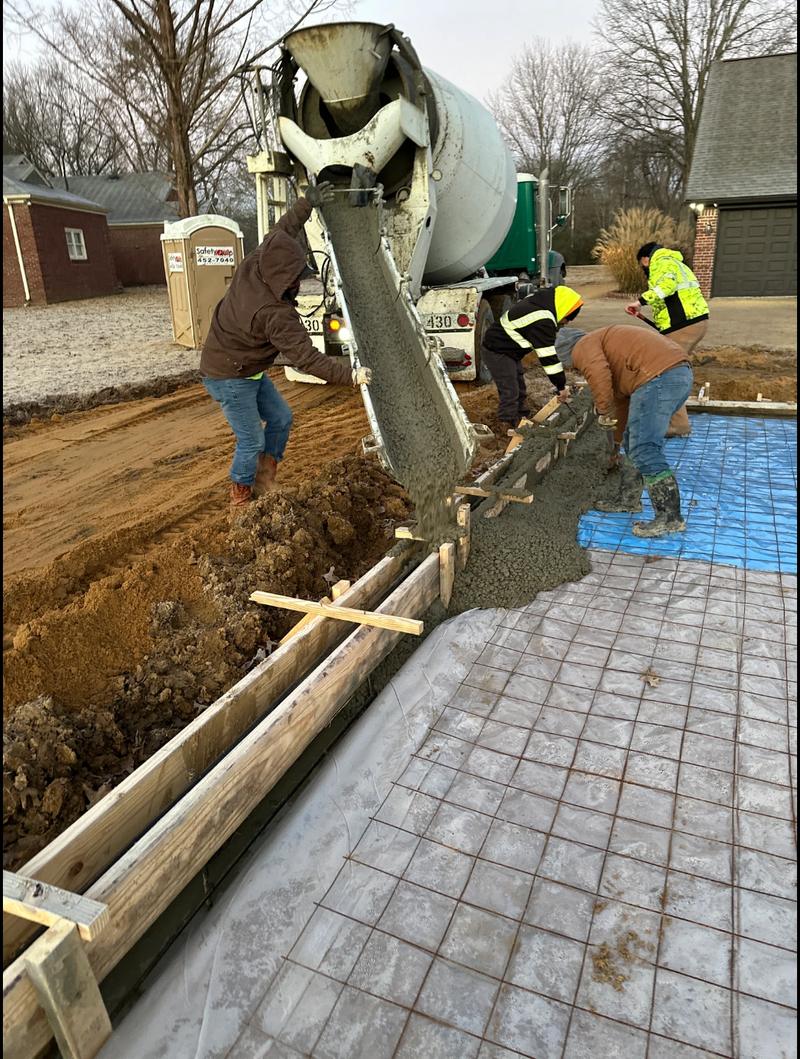 Crew placing concrete from a mixer chute over rebar mesh for a slab pour.